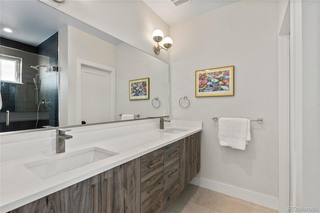 bathroom featuring double vanity, a shower stall, baseboards, and a sink