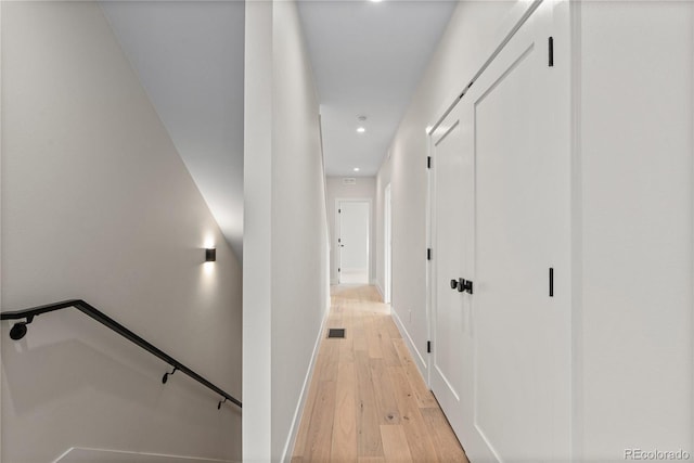 hallway with visible vents, baseboards, recessed lighting, light wood-style floors, and an upstairs landing