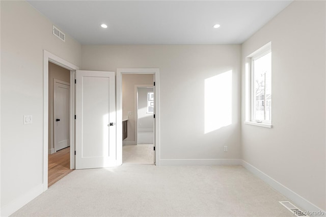 unfurnished bedroom with light carpet, visible vents, multiple windows, and recessed lighting