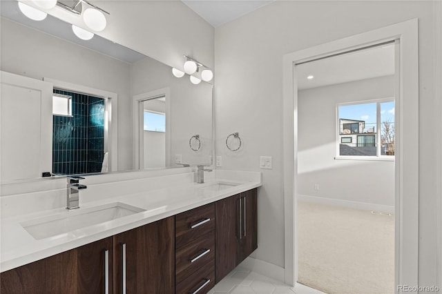 bathroom with a sink, baseboards, and double vanity