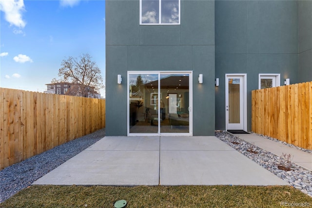 rear view of house featuring stucco siding, a patio, and a fenced backyard