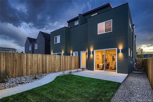 rear view of property featuring a lawn, stucco siding, a patio area, and a fenced backyard