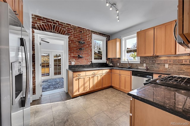 kitchen with tasteful backsplash, appliances with stainless steel finishes, sink, and dark stone countertops