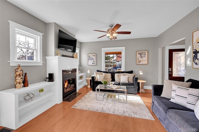 living room featuring ceiling fan, a premium fireplace, and hardwood / wood-style floors