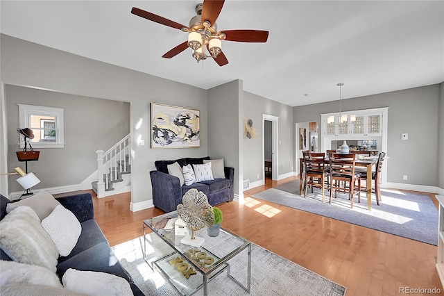 living room featuring ceiling fan with notable chandelier and light hardwood / wood-style floors