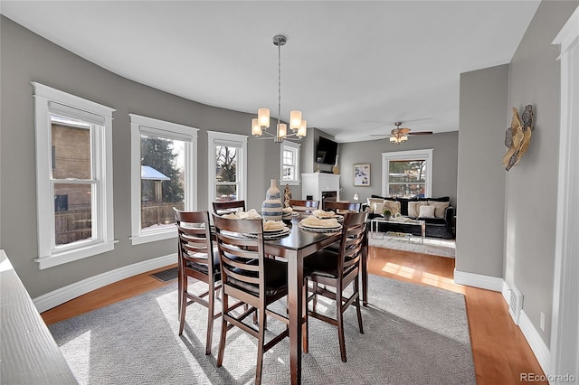 dining room featuring ceiling fan with notable chandelier and light wood-type flooring