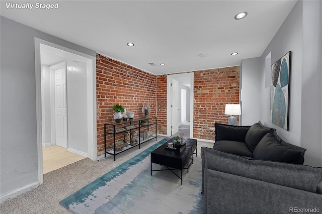 carpeted living room featuring brick wall