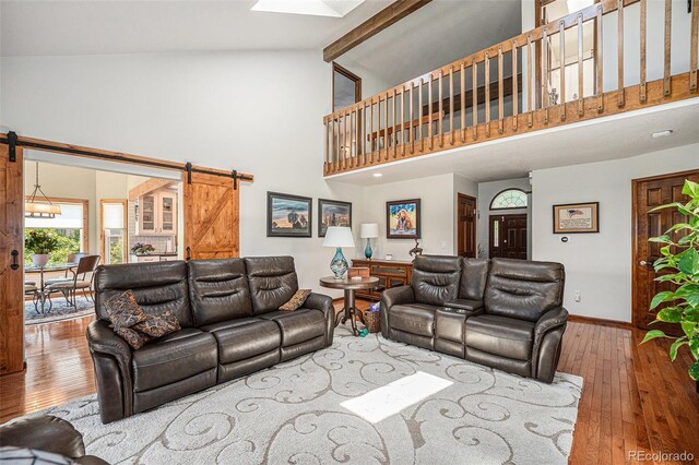 1152 Clubhouse Dr, Broomfield, CO 80020 - living area featuring a barn door, high vaulted ceiling, hardwood / wood-style floors, and baseboards