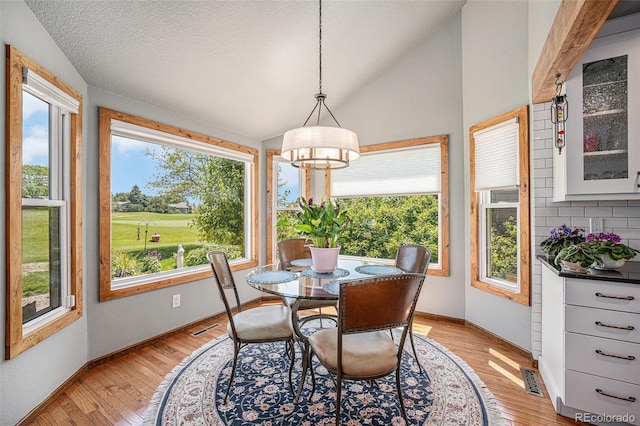 1152 Clubhouse Dr, Broomfield, CO 80020 - dining room with vaulted ceiling, light wood-style flooring, baseboards, a chandelier, and a textured ceiling