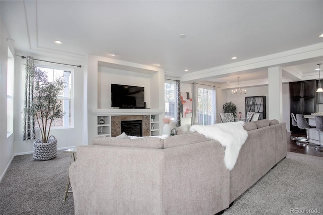 carpeted living room featuring a tray ceiling and a chandelier