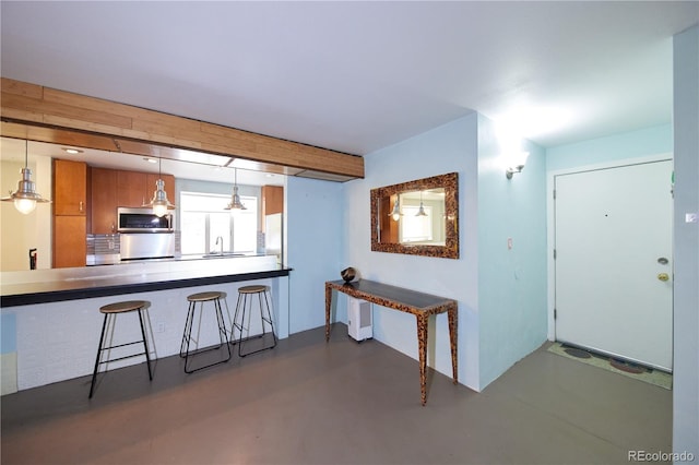 500 E 11th Ave Unit 201, Denver, CO 80203 - kitchen with stainless steel microwave, brown cabinets, concrete floors, decorative light fixtures, and a kitchen bar