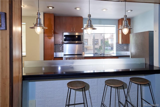 500 E 11th Ave Unit 201, Denver, CO 80203 - kitchen with appliances with stainless steel finishes, brown cabinetry, dark countertops, tasteful backsplash, and decorative light fixtures