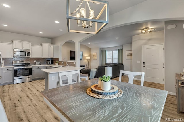 dining room featuring a notable chandelier, sink, and light hardwood / wood-style floors