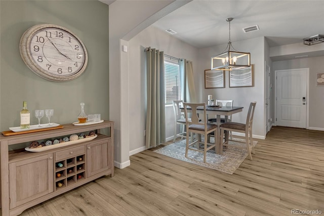 dining space featuring light wood-type flooring and a notable chandelier