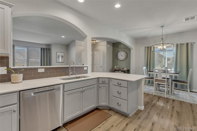 kitchen with dishwasher, light hardwood / wood-style flooring, sink, and a notable chandelier