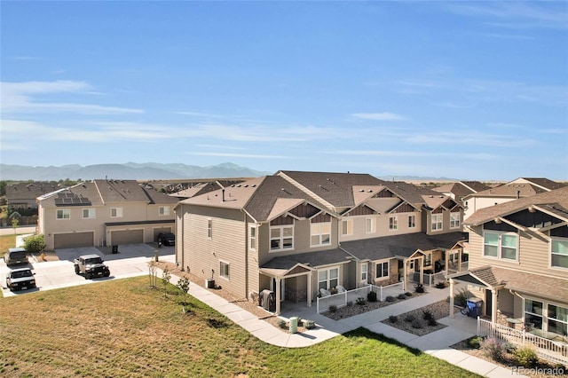 exterior space featuring a mountain view, a garage, and a lawn