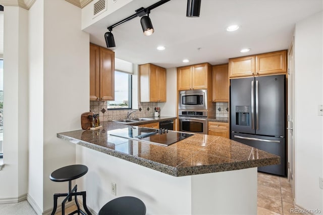 kitchen featuring kitchen peninsula, stainless steel appliances, sink, and a breakfast bar