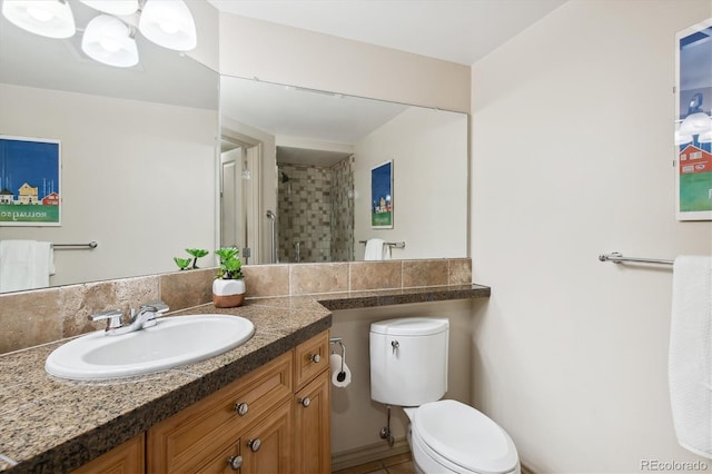 bathroom with tile patterned flooring, vanity, toilet, and a tile shower