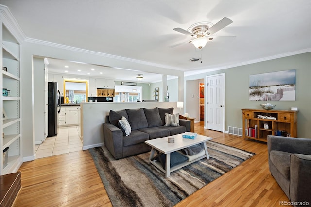 living room featuring ornamental molding, ceiling fan, and light wood-style floors