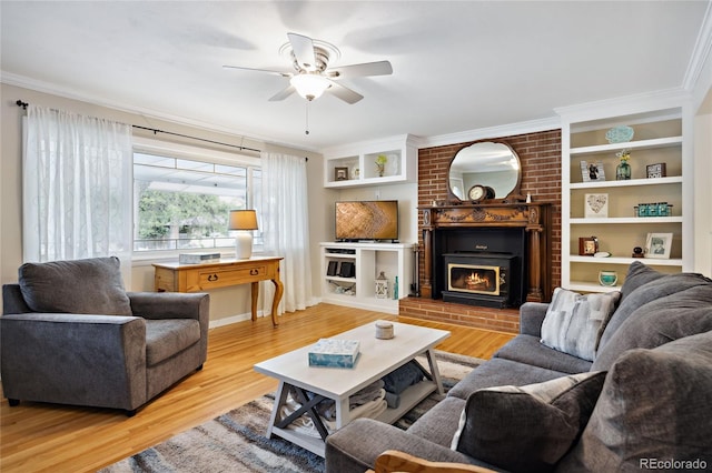 living area featuring ceiling fan, wood finished floors, ornamental molding, a fireplace, and built in shelves