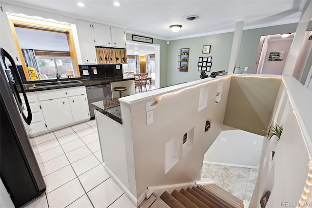 kitchen featuring a sink, freestanding refrigerator, stainless steel dishwasher, white cabinets, and tasteful backsplash