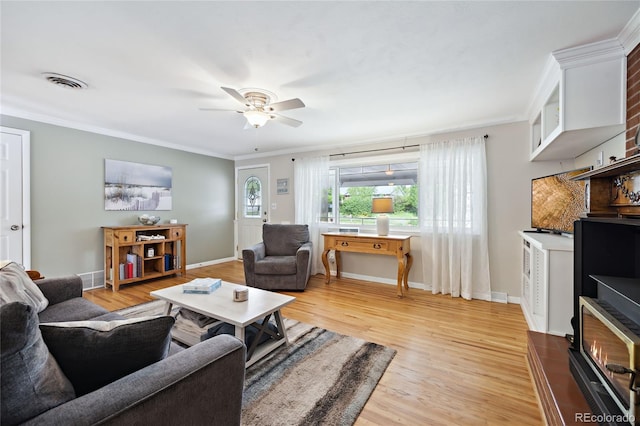 living room with light wood-style flooring, ornamental molding, ceiling fan, and baseboards