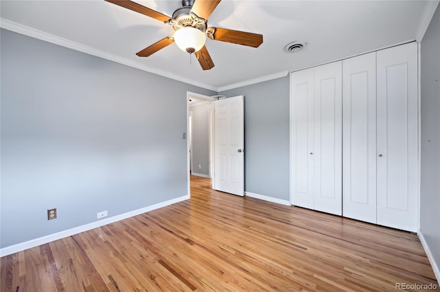 unfurnished bedroom featuring baseboards, ornamental molding, light wood-type flooring, a closet, and ceiling fan