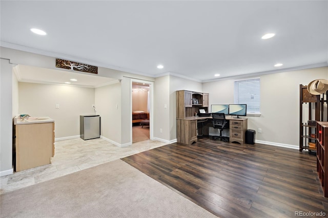 unfurnished office with recessed lighting, crown molding, baseboards, wood finished floors, and a sink