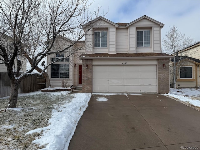 traditional-style home featuring concrete driveway, brick siding, an attached garage, and fence