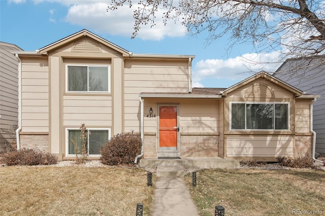 split level home with brick siding and a front lawn