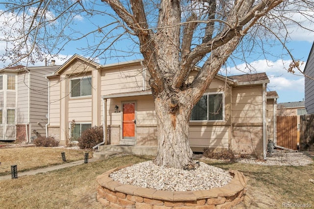 view of front of house featuring fence and brick siding