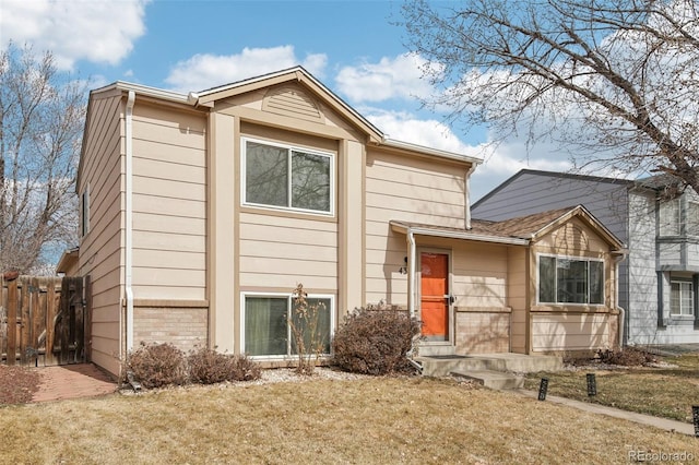 view of front of house with fence, a front lawn, and brick siding