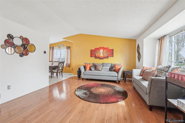 living room with lofted ceiling, a textured ceiling, baseboards, and wood finished floors