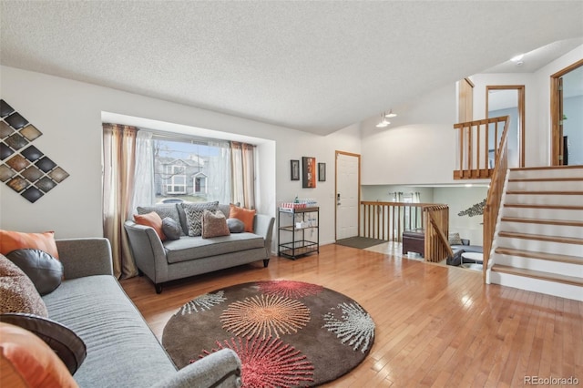 living room with a textured ceiling, stairway, vaulted ceiling, and hardwood / wood-style floors