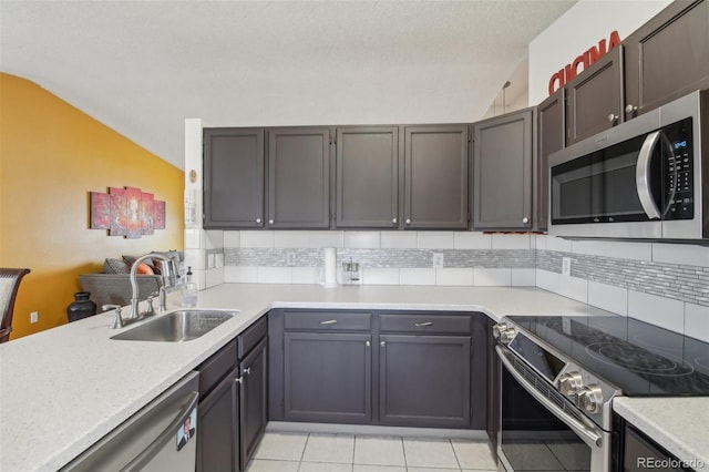 kitchen with tasteful backsplash, lofted ceiling, appliances with stainless steel finishes, light countertops, and a sink