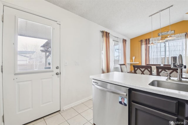 kitchen featuring light tile patterned floors, lofted ceiling, stainless steel dishwasher, a sink, and a textured ceiling