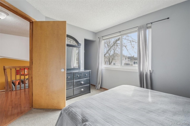 bedroom with a textured ceiling, carpet flooring, and baseboards