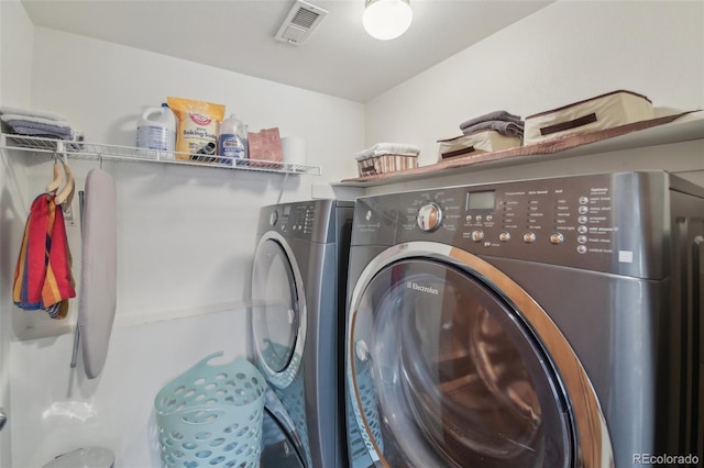 clothes washing area with laundry area, visible vents, and separate washer and dryer