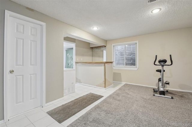 exercise room with tile patterned flooring, a textured ceiling, and baseboards