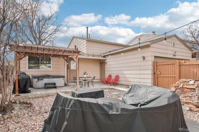 rear view of house with a garage, fence, a pergola, a patio area, and a hot tub