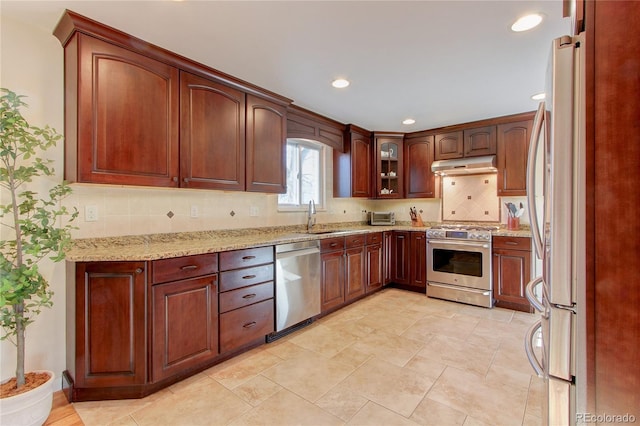 kitchen with backsplash, light stone countertops, sink, and stainless steel appliances