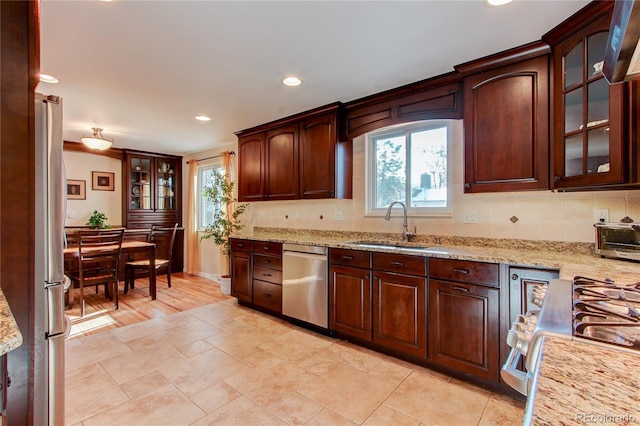 kitchen featuring stainless steel appliances, light stone counters, a wealth of natural light, and sink