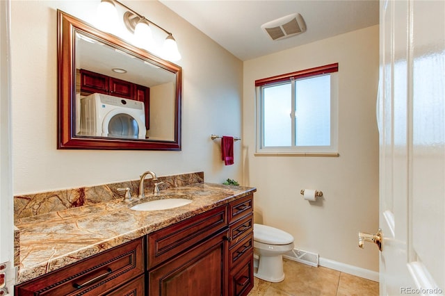 bathroom featuring tile patterned floors, toilet, vanity, and washer / dryer