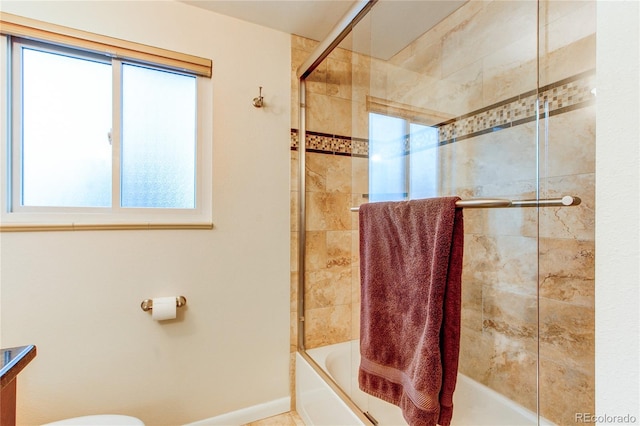 bathroom with toilet and shower / bath combination with glass door