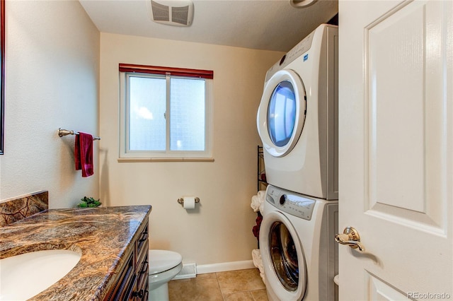 washroom with sink, stacked washer / dryer, and light tile patterned flooring