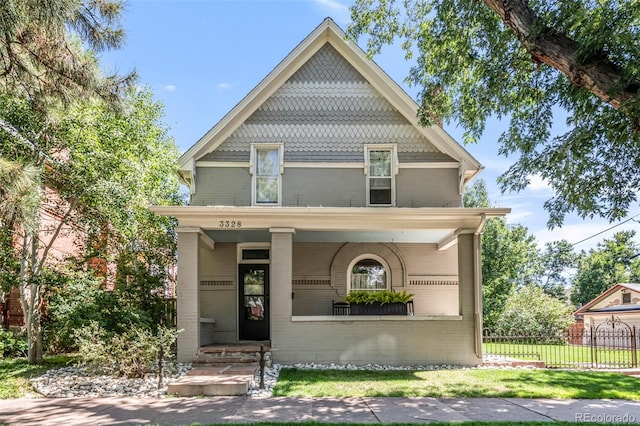 victorian home featuring fence, a porch, and brick siding