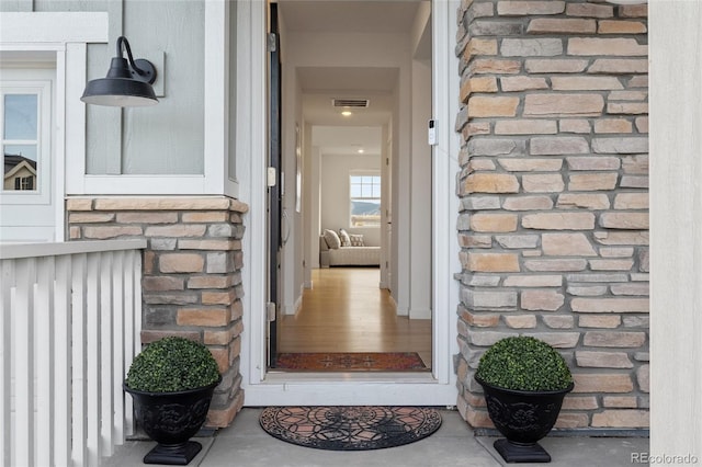 view of exterior entry featuring stone siding and visible vents