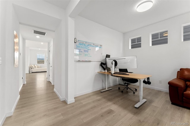 office featuring light wood-type flooring, visible vents, and baseboards