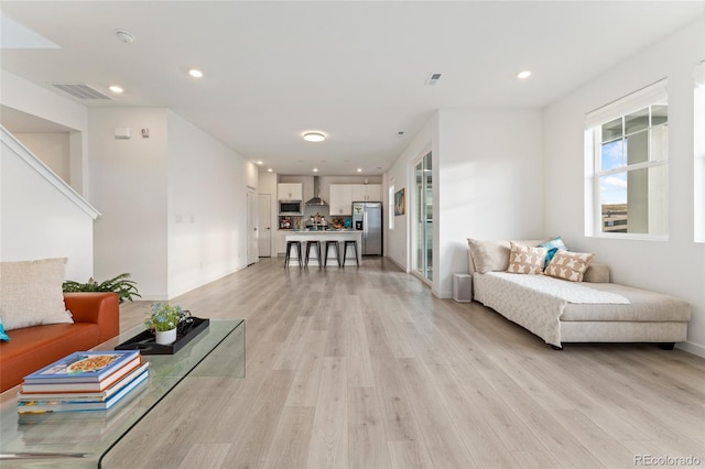 living room with light wood-type flooring, visible vents, and recessed lighting