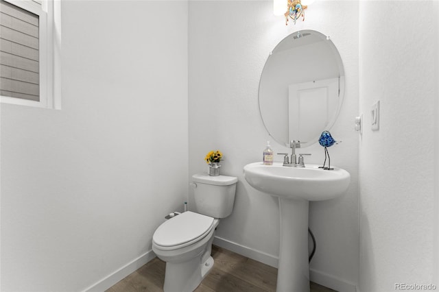 half bath with wood finished floors, toilet, and baseboards